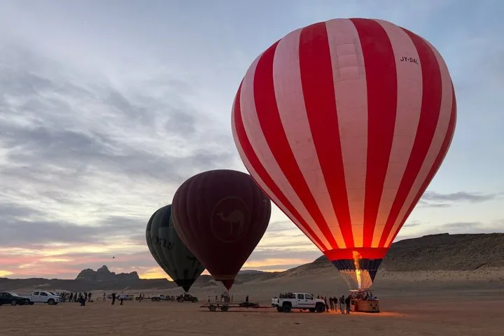 A hot air balloon over the sandstone mountains at sunrise on a Wadi Rum desert tour