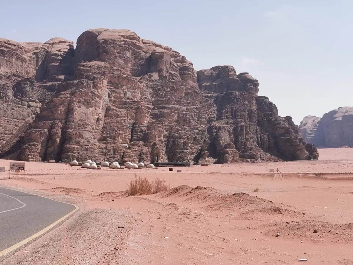 A Wadi Rum camp with traditional tents and dome pods below the cliffs