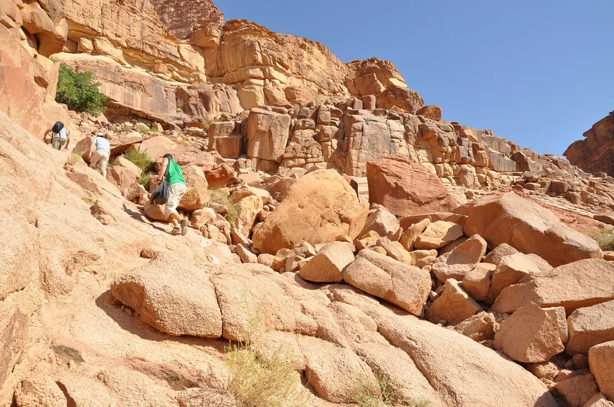 Travellers scrambling up the rocks on a Wadi Rum full day jeep tour